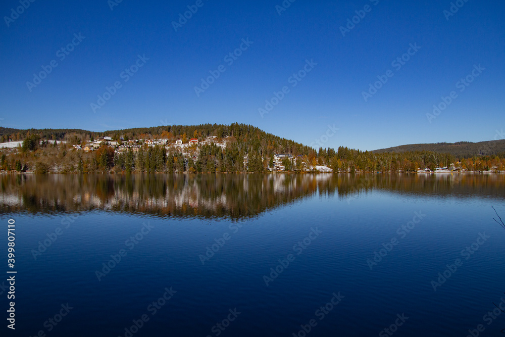 Titisee-Neustadt, Germany - 10 30 2012: surroundings of Titisee, european village in  beautiful winter cold day. Scenery is reflected in the lake. 