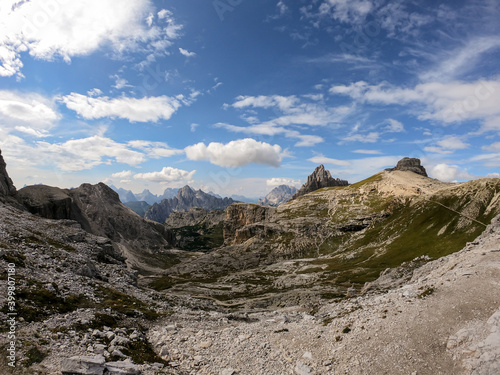 A panoramic view on a high and desolated mountain peaks in Italian Dolomites. The lower parts of the mountains are overgrown with moss and grass. Raw and unspoiled landscape. A bit of overcast.