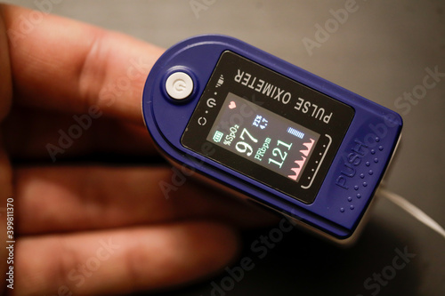 Details with the hand of a man measuring his pulse and blood oxygen level with a self use pulse oximeter at home during the Covid-19 outbreak.