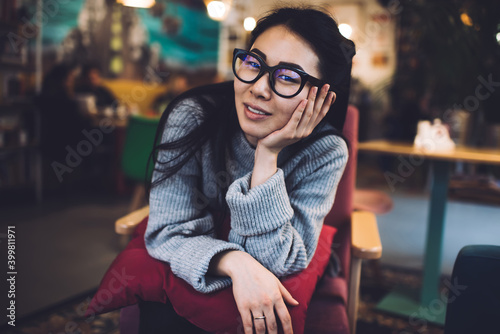 Glad Asian woman chilling in cafe during weekend
