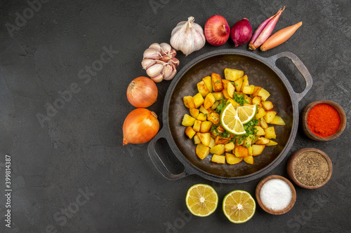 top view tasty fried potatoes inside pan with onions and garlics around on a dark background color cuisine meal food calorie