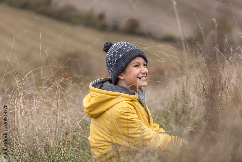 Happy little boy relaxing during autumn day in tall grass on a hill. Happy little boy relaxing during autumn day in tall grass on a hill.