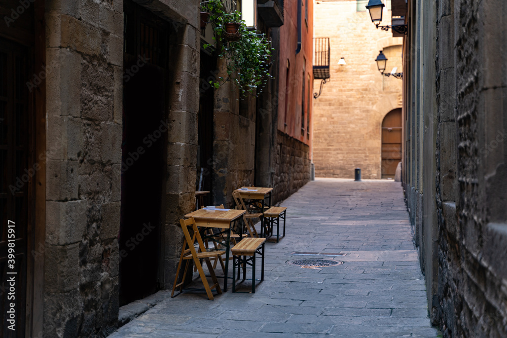 Cafe with terrace on a narrow street with medieval historic houses in Barcelona