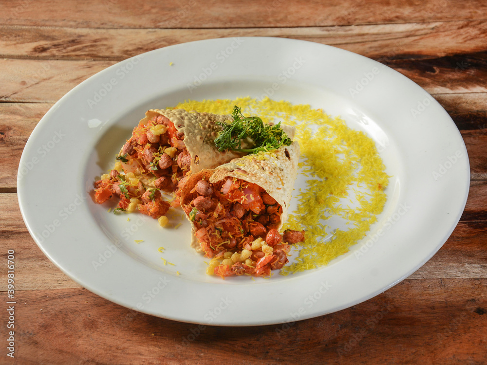 Masala Papad cone is a delicious Indian snack made using rolled roasted or fried papad topped with a tangy and spicy onion tomato mix, served over a rustic wooden background, selective focus