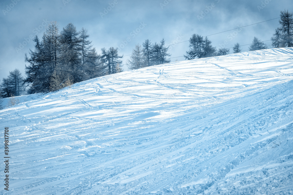 Mountain ski slope background on the skiing resort. Active winter holiday. European ski resort in alpine mountains. Ski and snowboard free ride tracks in powder snow