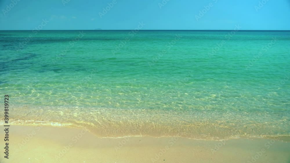 Exotic beach by the ocean with rolling waves on the sandy shore and blue sky Exotic beach by the ocean with rolling waves on the sandy shore and blue sky