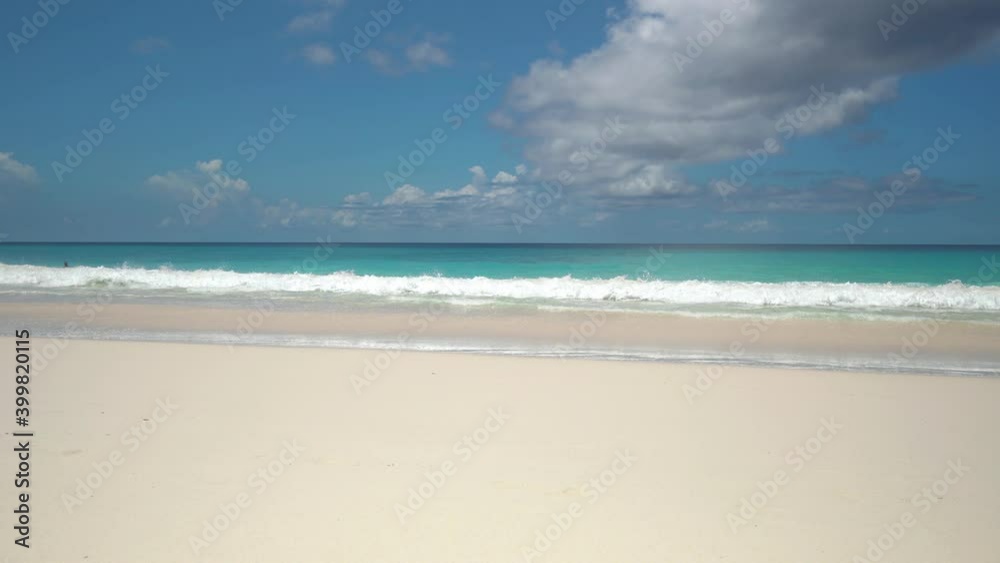 Exotic beach by the ocean with rolling waves on the sandy shore and blue sky Exotic beach by the ocean with rolling waves on the sandy shore and blue sky