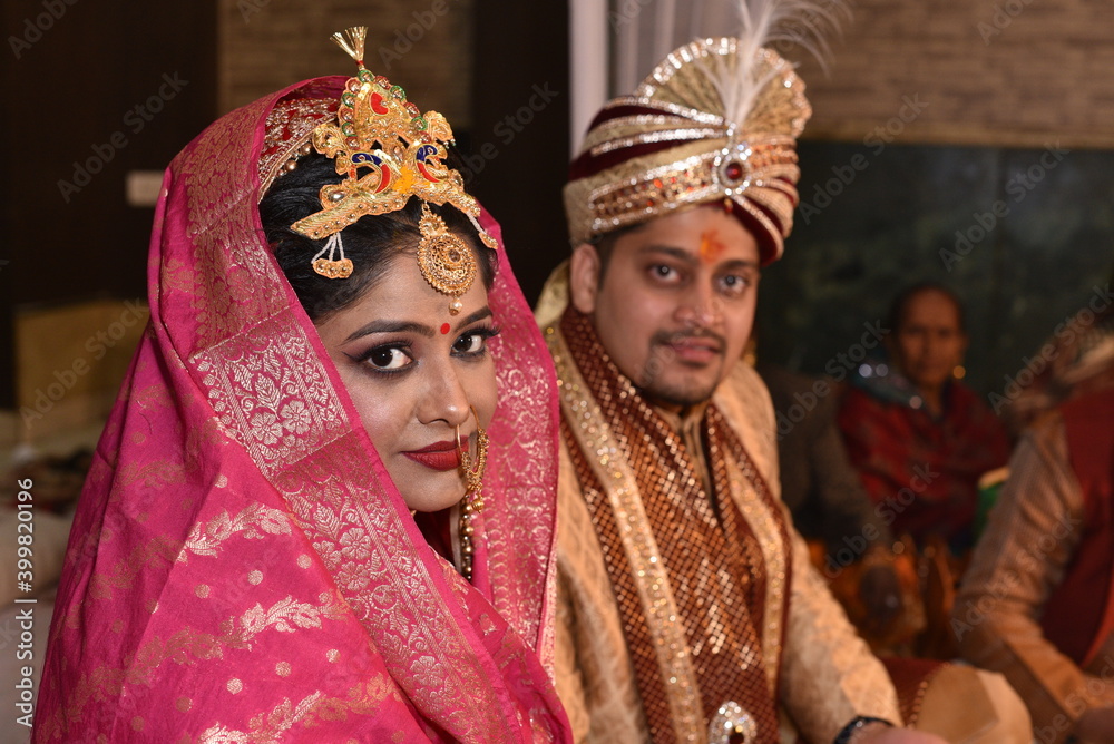 Indian wedding couple posing for photograph. Beautiful bridal makeup of bride is visible with groom in bokeh effect
