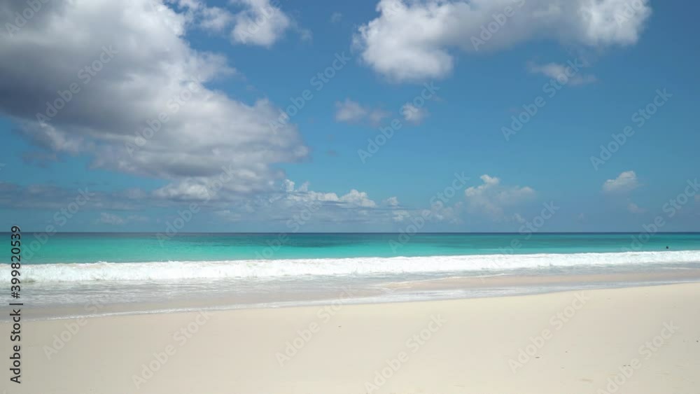 Exotic beach by the ocean with rolling waves on the sandy shore and blue sky Exotic beach by the ocean with rolling waves on the sandy shore and blue sky