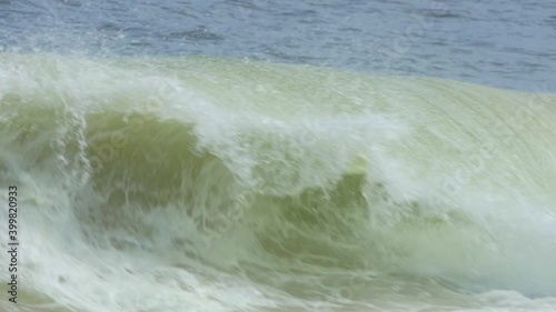 Wave breaks at shore on the sand sunny day, slow motion HD 96 fps photo