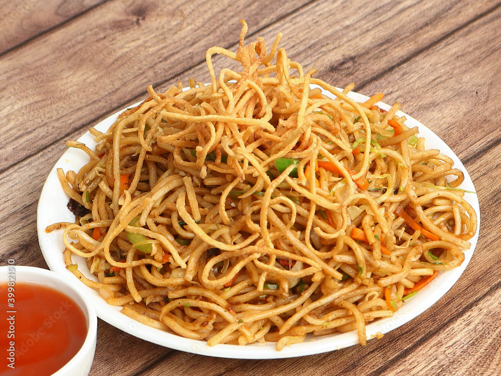 Veg Hakka Noodles a popular oriental dish made with noodles and vegetables, served over a rustic wooden background, selective focus