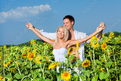 Happy beautiful young couple in a field of sunflowers