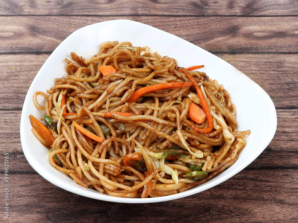 Veg Noodles a popular indo-chinese dish made with noodles and vegetables, served over a rustic wooden background, selective focus
