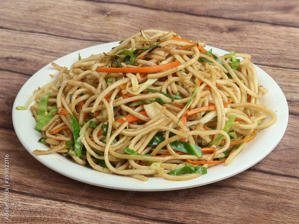 Veg Noodles a popular indo-chinese dish made with noodles and vegetables, served over a rustic wooden background, selective focus