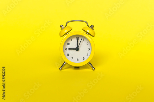Ringing twin bell vintage classic alarm clock isolated on yellow background. Rest hours time of life good morning night wake up awake concept.