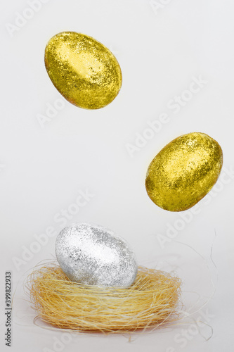 Illuminating Gold and silver Easter eggs levitation to the nest on a Ultimate Grey background. Easter concept.