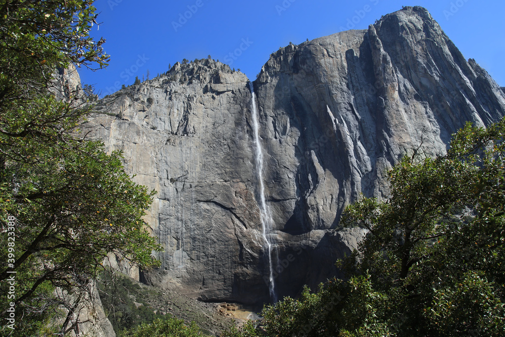 Yosemite falls in yosemite National Park with blue sky and trees in front