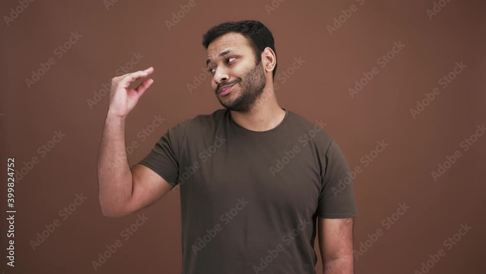 Studio portrait of boring indian man making blah blah gesture with his hand, expressing disbelief, brown background Studio portrait of boring indian man making blah blah gesture with his hand, expressing disbelief, brown background