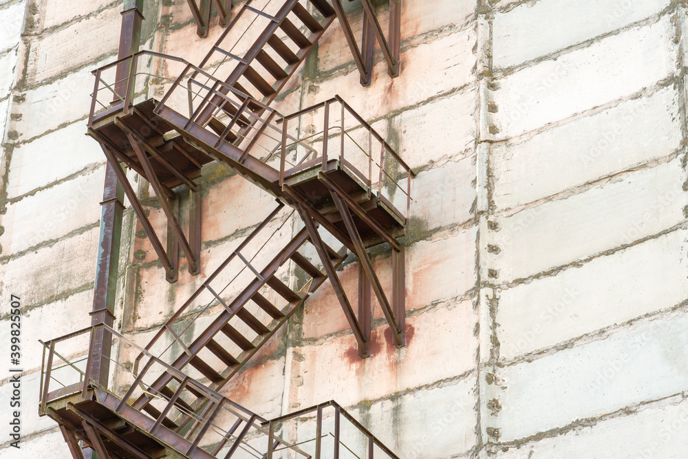 External metal staircase on the facade of an abandoned factory or enterprise building.