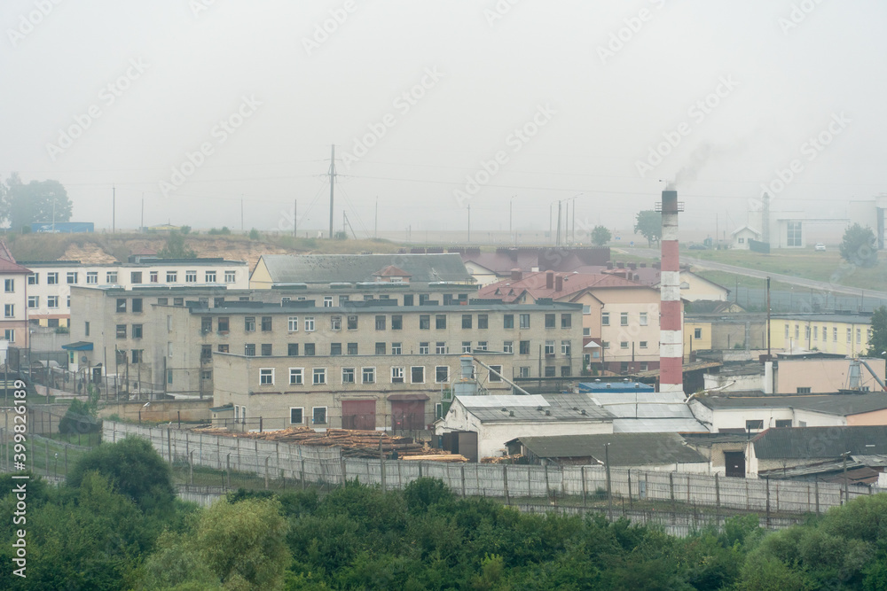 old abandoned factory building in the middle of a green forest. Panorama of the city with a view of factories and enterprises. Devastation and desolation in the third world. 