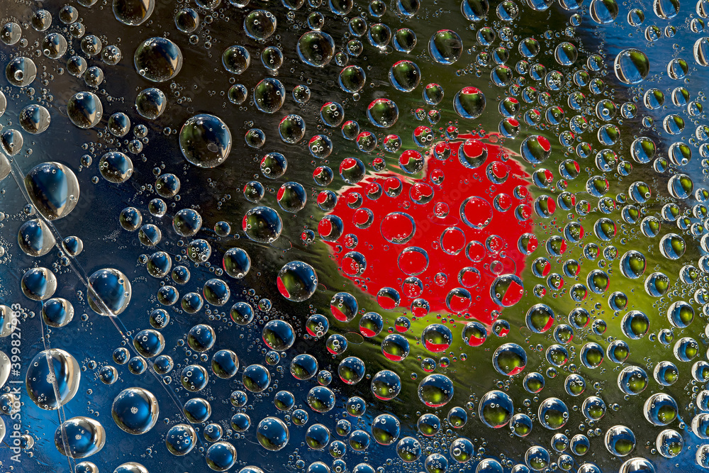 Multi colored drops of water are located on a blue-green background with a red silhouette of the heart. Abstract fantasy. Multi colored drops of water are located on a blue-green background with a red silhouette of the heart. Abstract fantasy.