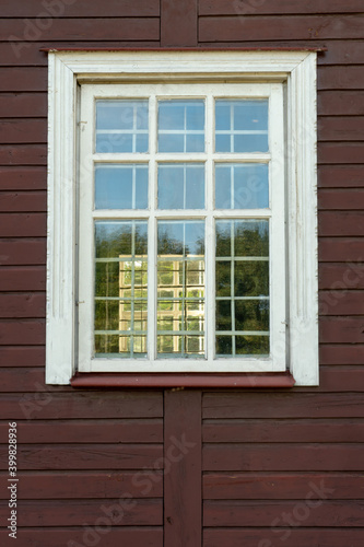 White wooden antique window on a wooden building. Old well-kept wooden house. Old Church and Windows with a cross.