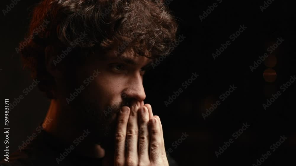 Close-up face of bearded young man reading online message while looking at laptop screen, slow motion. Tilt down shot of happy male looks at an important message and typing the answer at dark room. Close-up face of bearded young man reading online message while looking at laptop screen, slow motion. Tilt down shot of happy male looks at an important message and typing the answer at dark room.