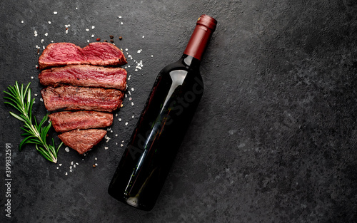 Different degrees of roasting heart-shaped beef steak with spices and bottle of wine on a stone background. valentines day celebration concept