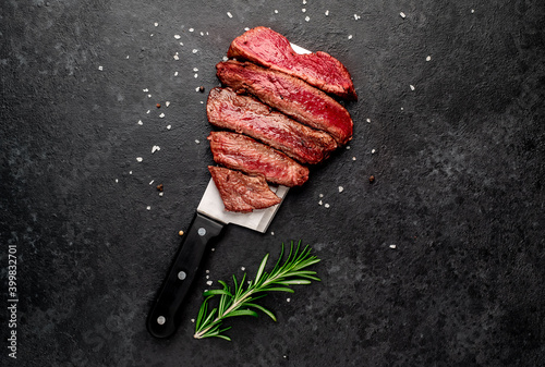 Different degrees of roasting heart shaped beef steak with spices on a meat knife on a stone background with copy space for your text