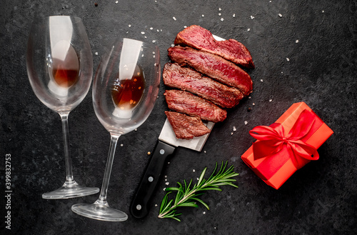 Different degrees of roasting beef steak in the shape of a heart with spices and glasses of wine on a stone background. valentines day celebration concept