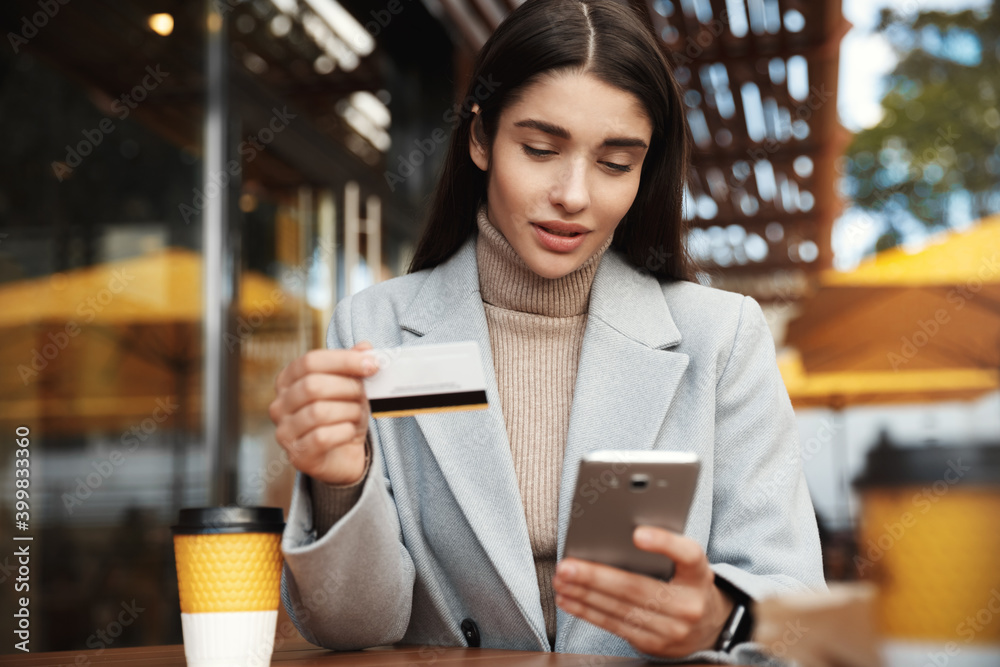 © Liubov Levytska - Young woman paying online, using credit card and mobile phone while sitting in coffee shop, transfer money via smartphone or shopping in internet © Liubov Levytska - Young woman paying online, using credit card and mobile phone while sitting in coffee shop, transfer money via smartphone or shopping in internet