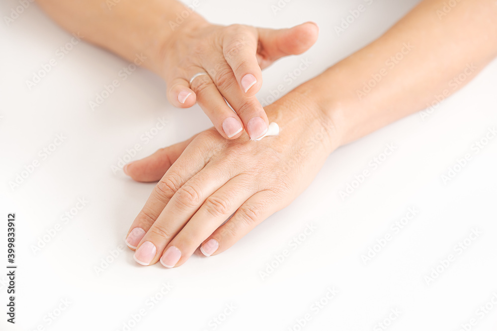 Naklejka premium woman's right hand applying cream on her left hand. Self care concept