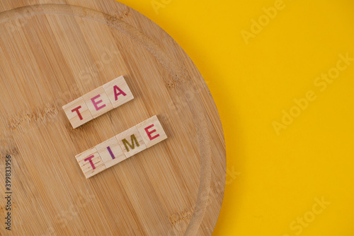 Tea menu concept. Scrabble letter tiles on wooden table. Yellow background.