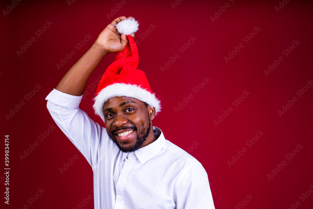 brazilian man wear santa claus headwear isolated over red color background brazilian man wear santa claus headwear isolated over red color background