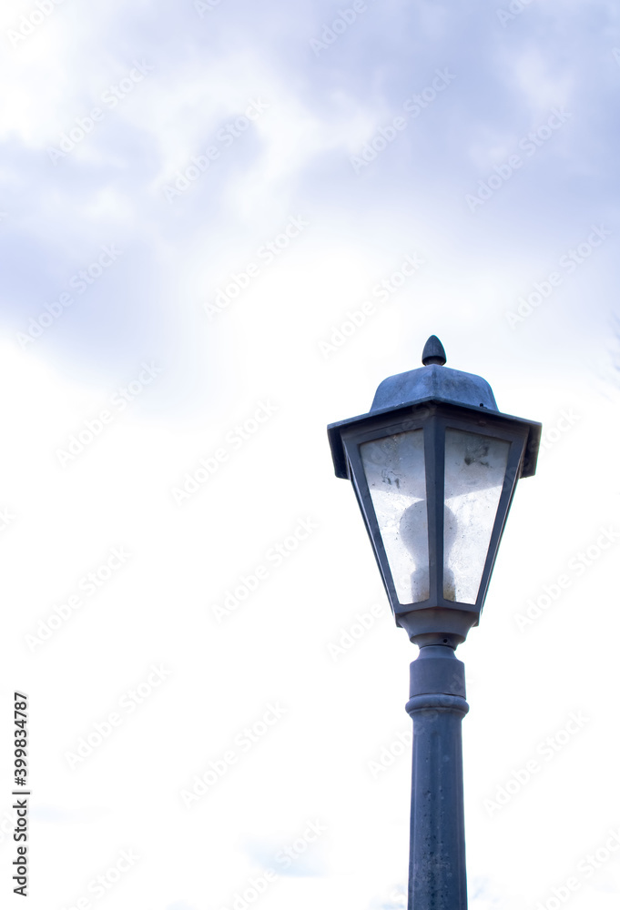 Street lamp with a classic lamppost against a cloudy sky background. Vintage style outdoor lamppost