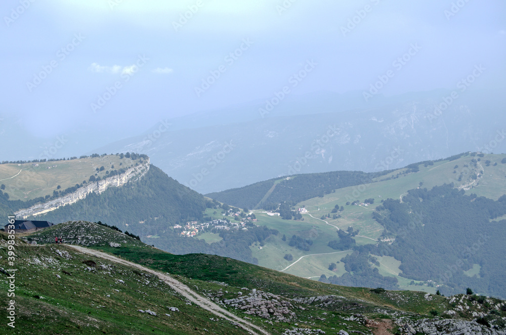 Naklejka premium Beautiful view of the peaks of Monte Baldo. Stunning cloudy and panoramic view. Green Pastures in Italian Alps