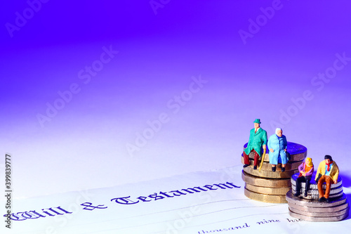 Conceptual image of miniature a figure couples sat on coins at the side of a last will and testament document, photo