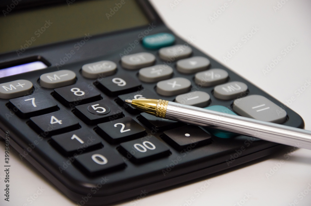 calculator and pen lie on a white background calculator and pen lie on a white background