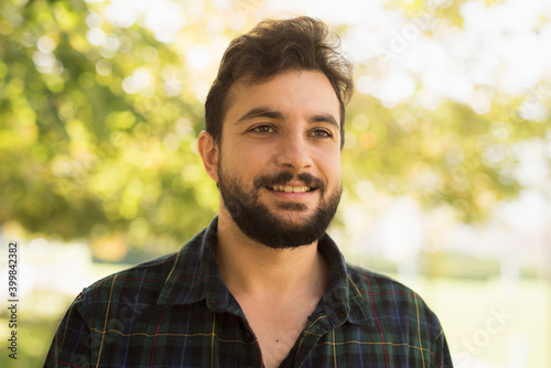 Bearded man in outdoors park. Smiling disheveled
