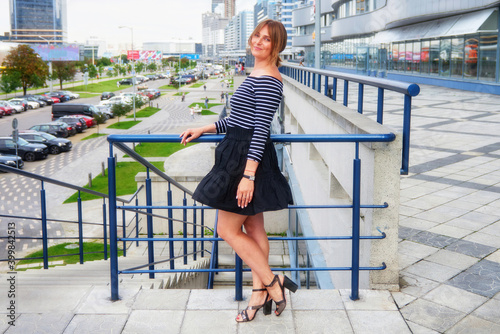 Beautiful young woman posing against the backdrop of a modern office building.
