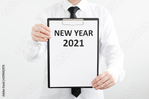 man's hands hold a tablet with New year 2021 on a gray background, concept of New year. Business goals and vision.