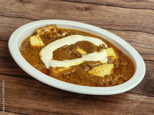 Paneer Butter Masala or Cheese Cottage Curry, served over a rustic wooden background, selective focus © Mahi