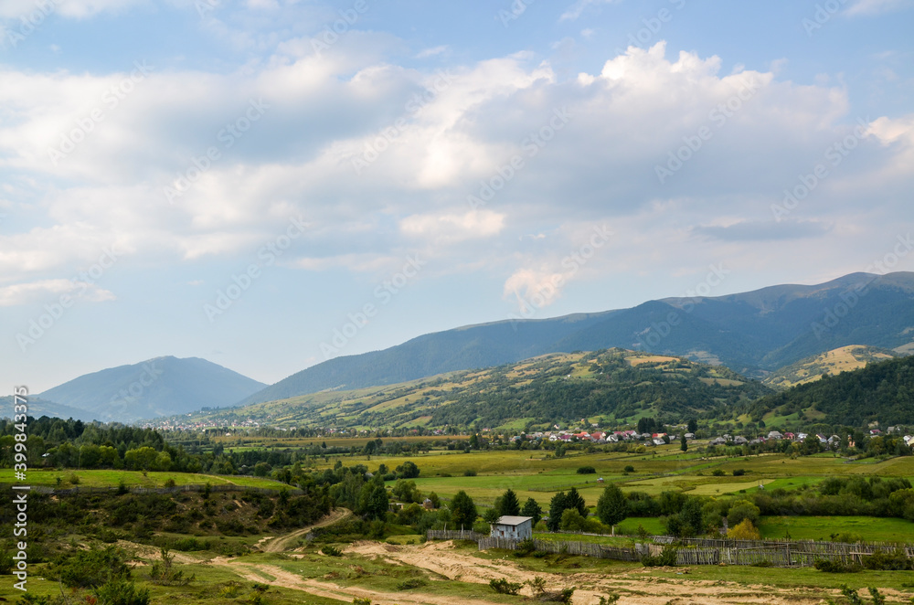 Beautiful countryside landscape with forested hills and grassy fields. Carpathian village in summer