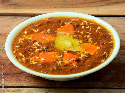 Paneer Butter Masala or Cheese Cottage Curry, served over a rustic wooden background, selective focus