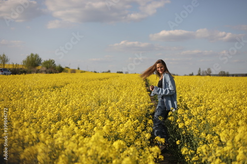 young beautiful woman in a field with yellow blooming rapeseed. girl in yellow floral field, rapeseed plantation, summer vacation concept © Andriy Medvediuk