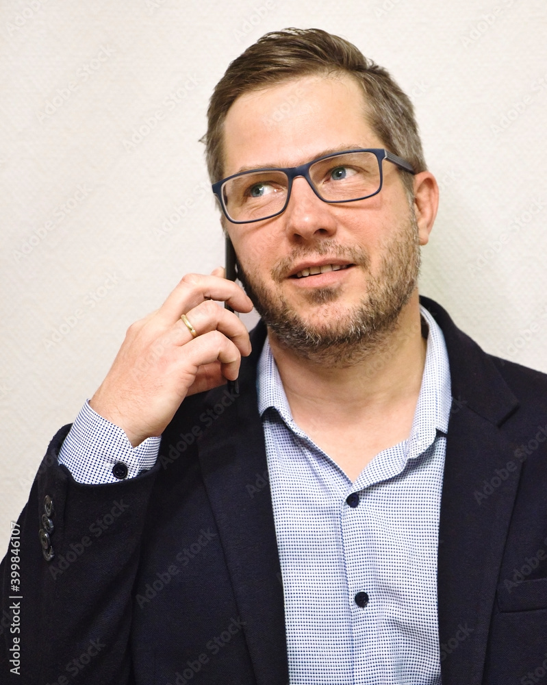 Caucasian unshaven business man in glasses talking on the smartphone and looking away from the camera. Isolated on white background Caucasian unshaven business man in glasses talking on the smartphone and looking away from the camera. Isolated on white background