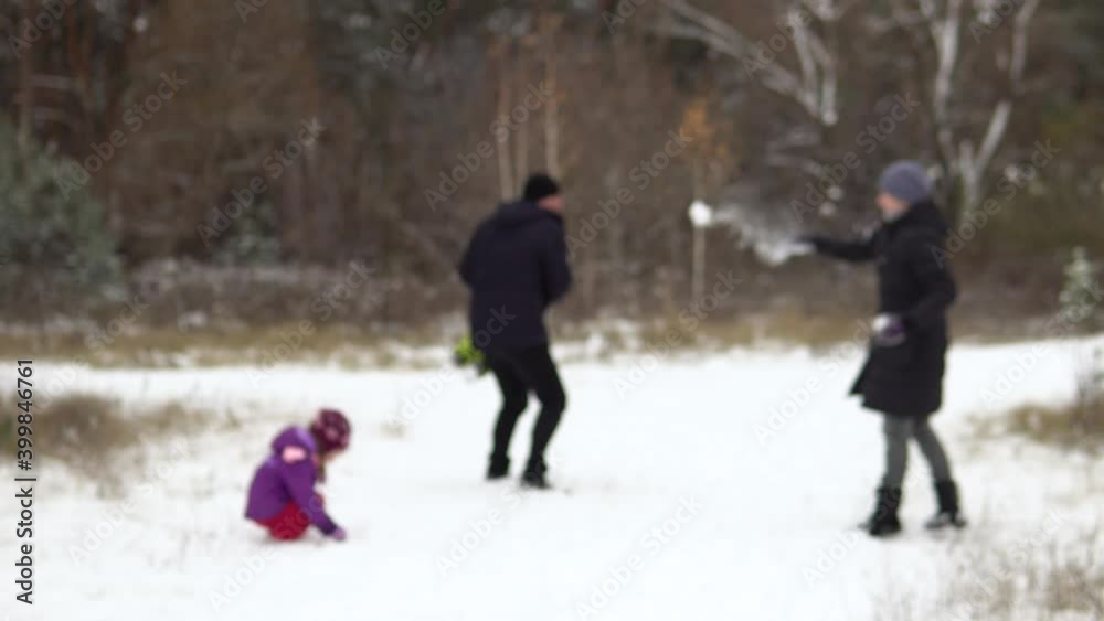 Blurred image of a family of four: mom, dad, son and daughter are playing snowballs in nature. Blurred background. Camping with the family.4k Blurred image of a family of four: mom, dad, son and daughter are playing snowballs in nature. Blurred background. Camping with the family.4k