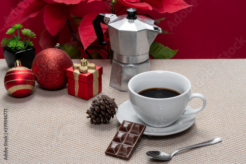 christmas coffee cup of coffee and a chocolate bar on a beige towel with christmas decoration on red background photo