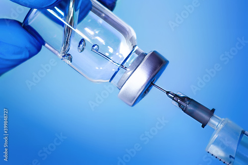 Vaccine in a bottle with a syringe on a blue background.The concept of medicine, healthcare and science.Coronavirus vaccine