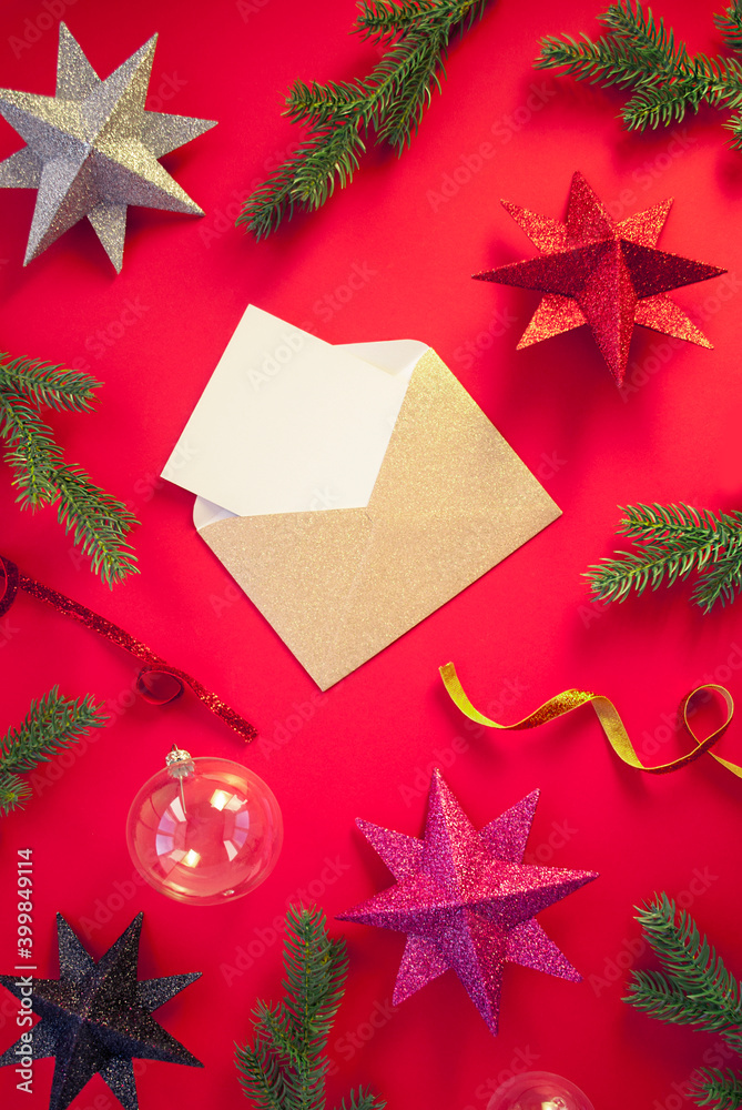 Spruce branches, decorative balls with stars on red background with envelope and paper card note. Christmas composition. Happy New Year. Space for text. Flat lay, top view